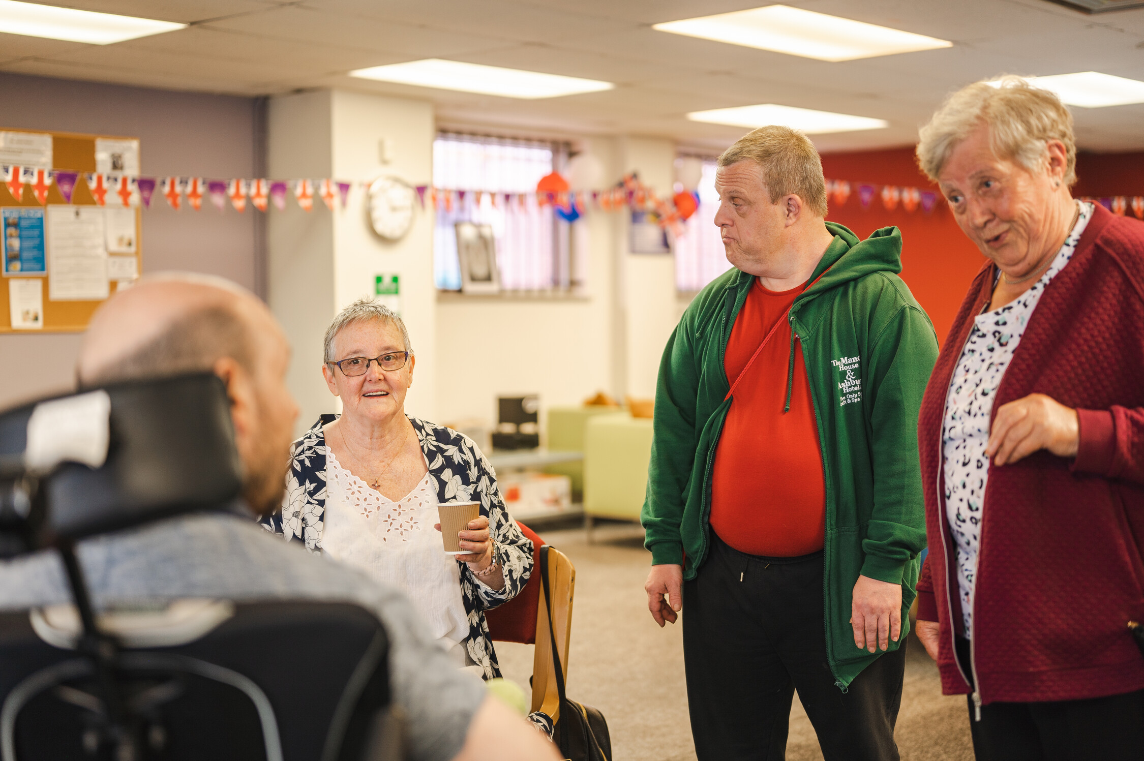 This is an image of four people talking, two women, a man and someone in a wheelchair.