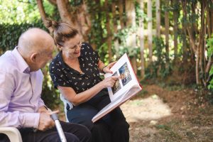This is an image of two people looking at a photography book. One is an older man and the other person is a woman.