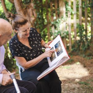 This is an image of two people looking at a photography book. One is an older man and the other person is a woman.