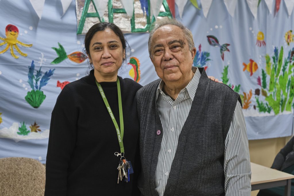 This is an image of a man and woman. The woman is wearing black and a lanyard and the man is wearing a shirt with a gilet.