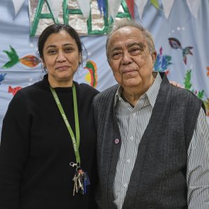 This is an image of a man and woman. The woman is wearing black and a lanyard and the man is wearing a shirt with a gilet.