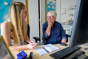 This is an image of a young woman and an older woman talking to each other in front of a computer.