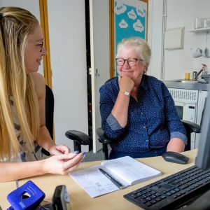 This is an image of a young woman and an older woman talking to each other in front of a computer.