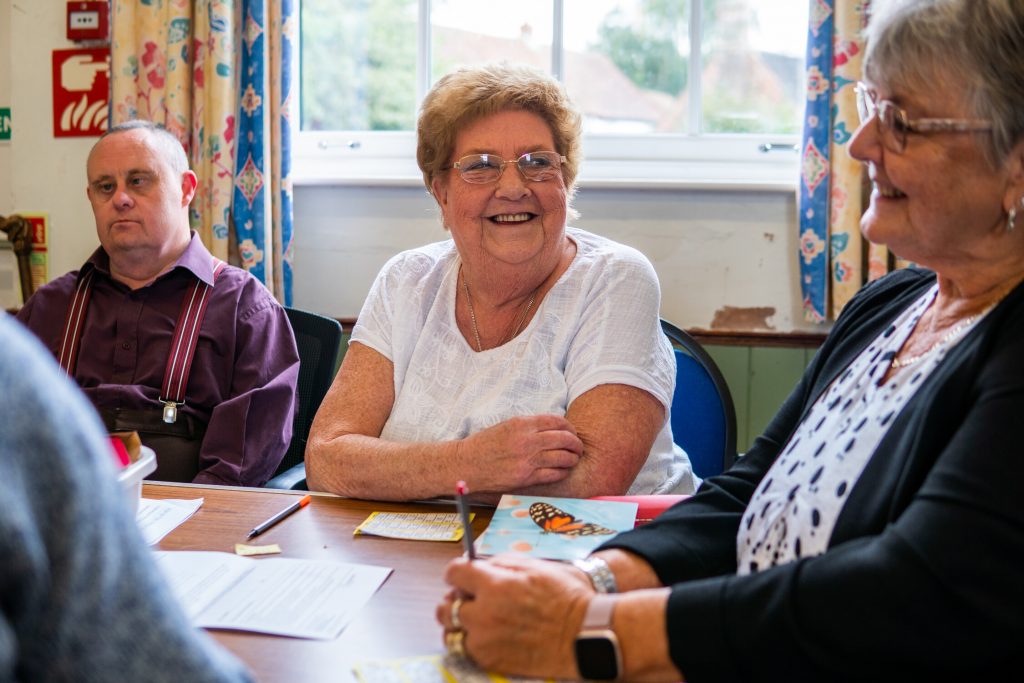 This in image of 2 women and a man talking around a table in a group setting.