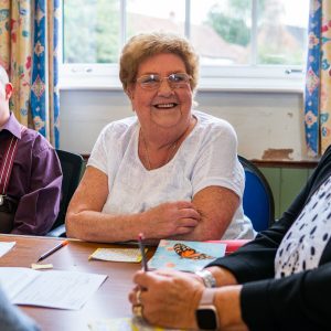 This in image of 2 women and a man talking around a table in a group setting.