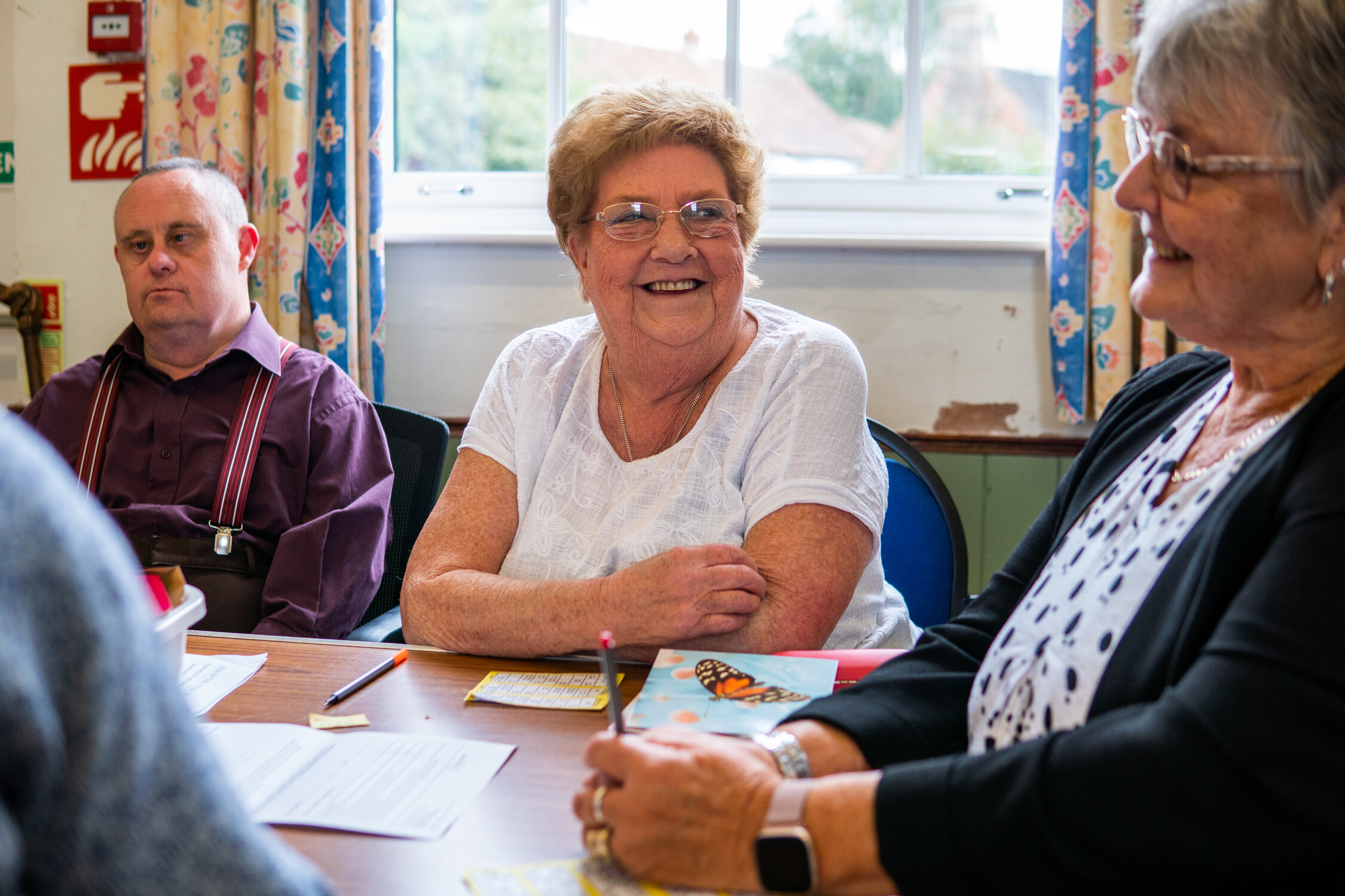 This in image of 2 women and a man talking around a table in a group setting.
