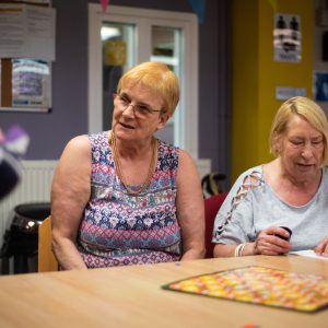 This is an image of 2 women sat around a table in a group setting.