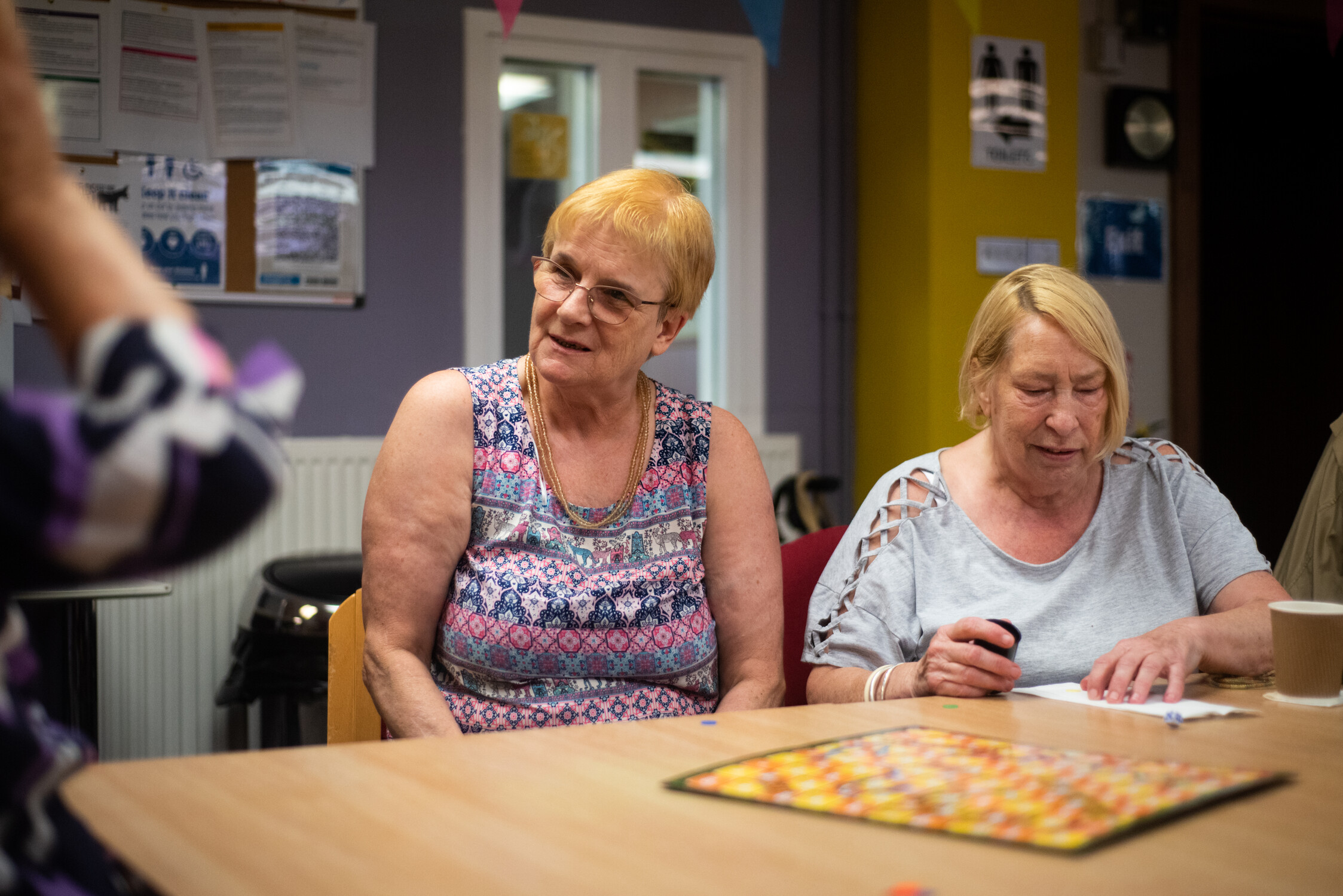 This is an image of 2 women sat around a table in a group setting.