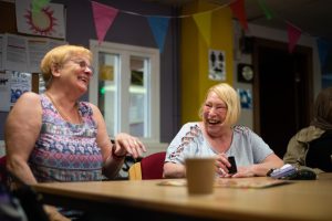 This is an image of two women speaking round a table.
