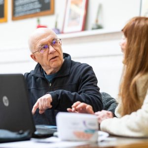 Image of a man talking to a woman in front of a laptop