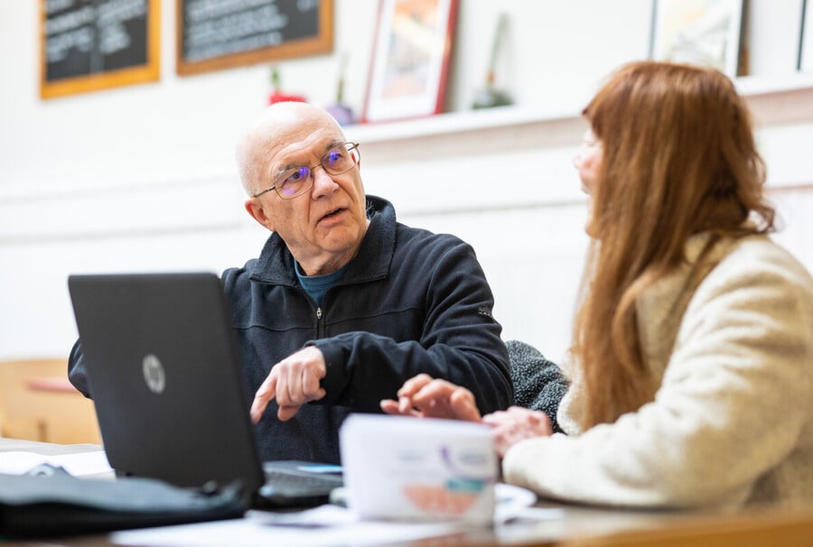 Image of a man talking to a woman in front of a laptop