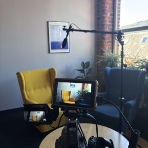 Image of filming of advice videos. There is a camera and two chairs.