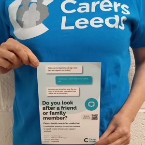 Image of a Carers Leeds staff member holding a carers Leeds leaflet
