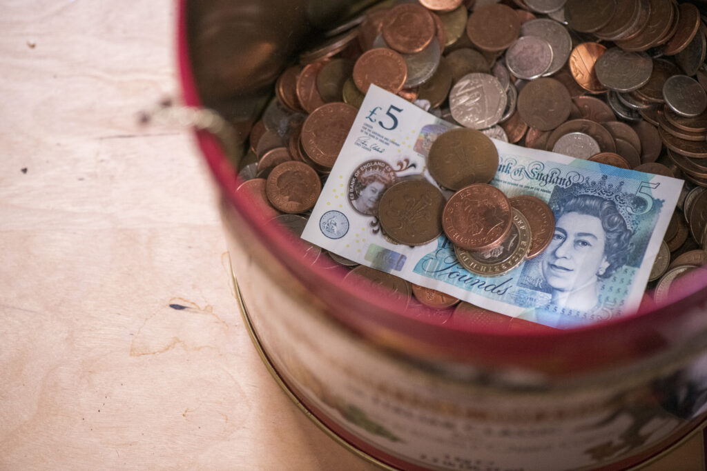 Image of a tin of money and a 5 pound note