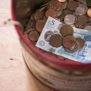 Image of a tin of money and a 5 pound note
